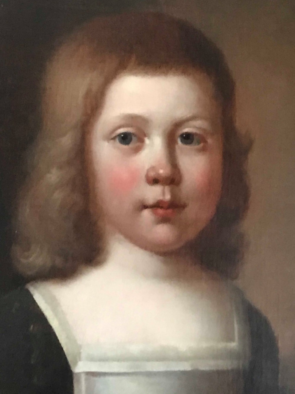 An antique seventeenth-century oil portrait of a young boy with light brown hair in period dress, set in a carved gilt frame. View II