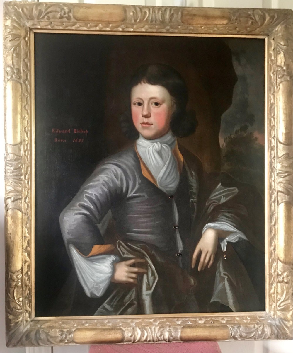 An antique oil portrait of a young man wearing a grey coat and white cravat, encased in a carved giltwood frame.