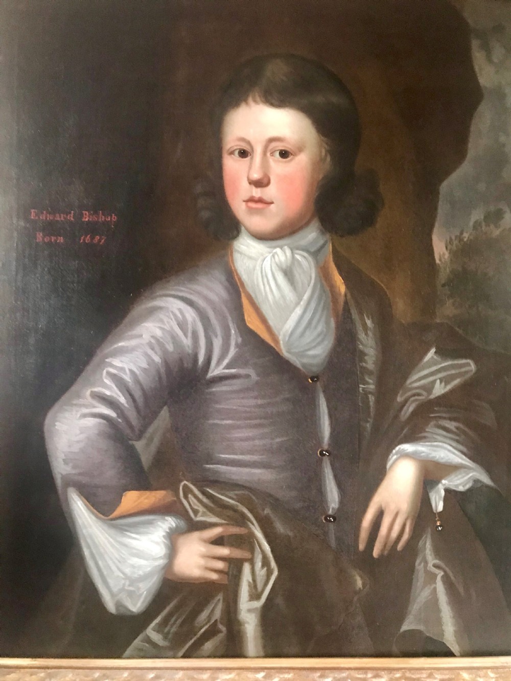 An antique oil portrait of a young man wearing a grey coat and white cravat, encased in a carved giltwood frame. View II