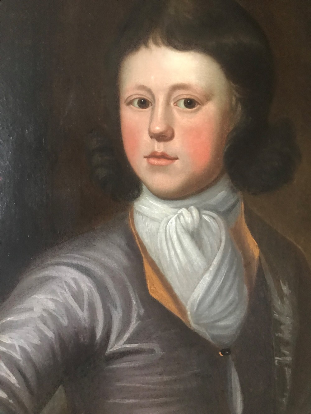 An antique oil portrait of a young man wearing a grey coat and white cravat, encased in a carved giltwood frame. View III