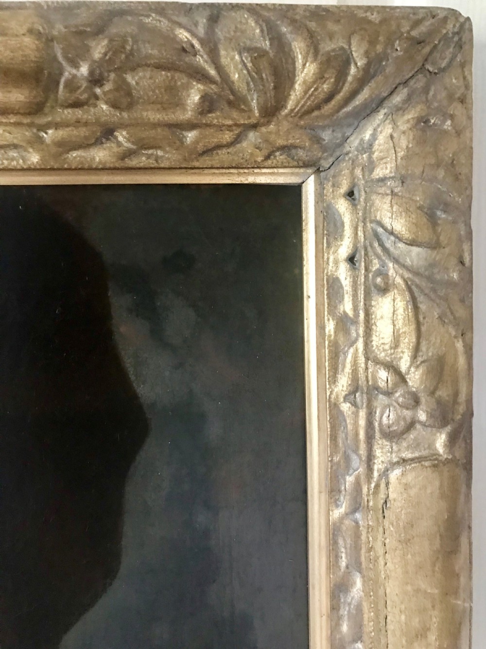 An antique oil portrait of a young man wearing a grey coat and white cravat, encased in a carved giltwood frame. View V