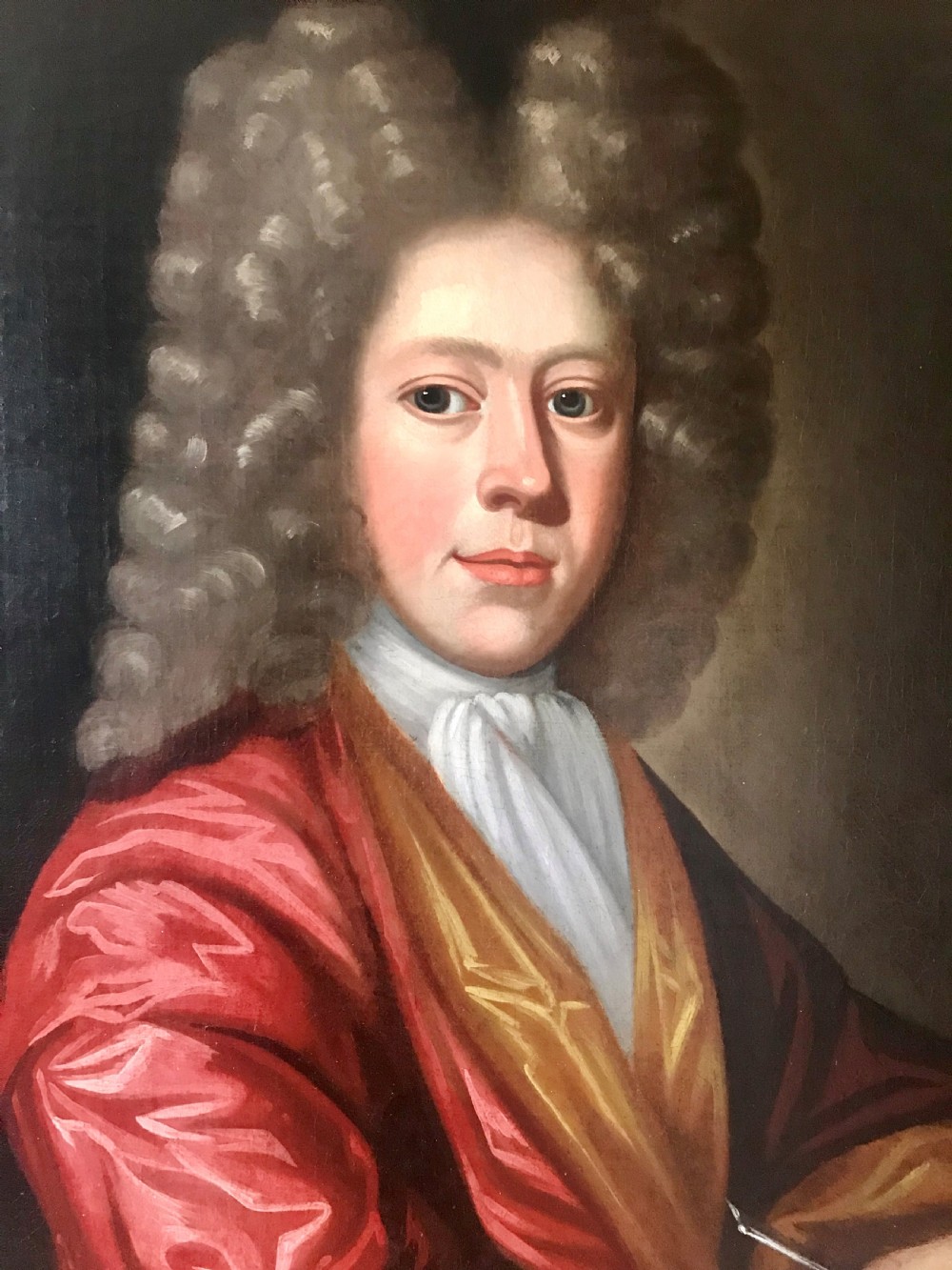 An early 18th-century oil painting on canvas depicting a gentleman in a full wig and red silk robe writing in a book, presented within a gilded frame. View III