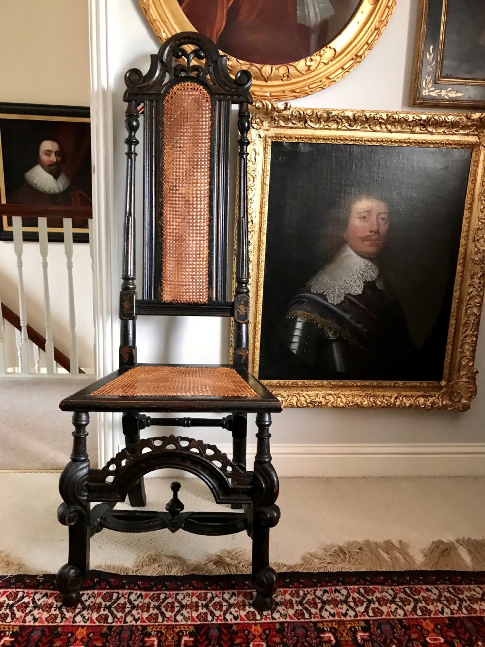 A tall-backed black japanned side chair featuring a cane seat panel, a central woven cane splat, turned uprights, and carved cresting.