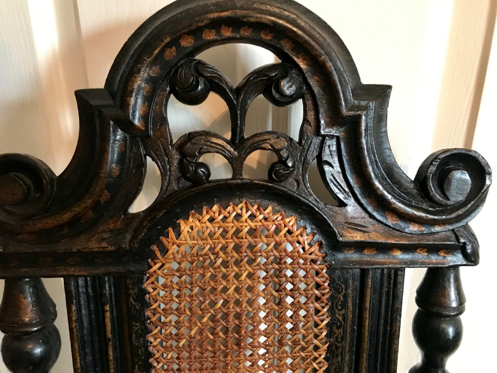 A tall-backed black japanned side chair featuring a cane seat panel, a central woven cane splat, turned uprights, and carved cresting. View III