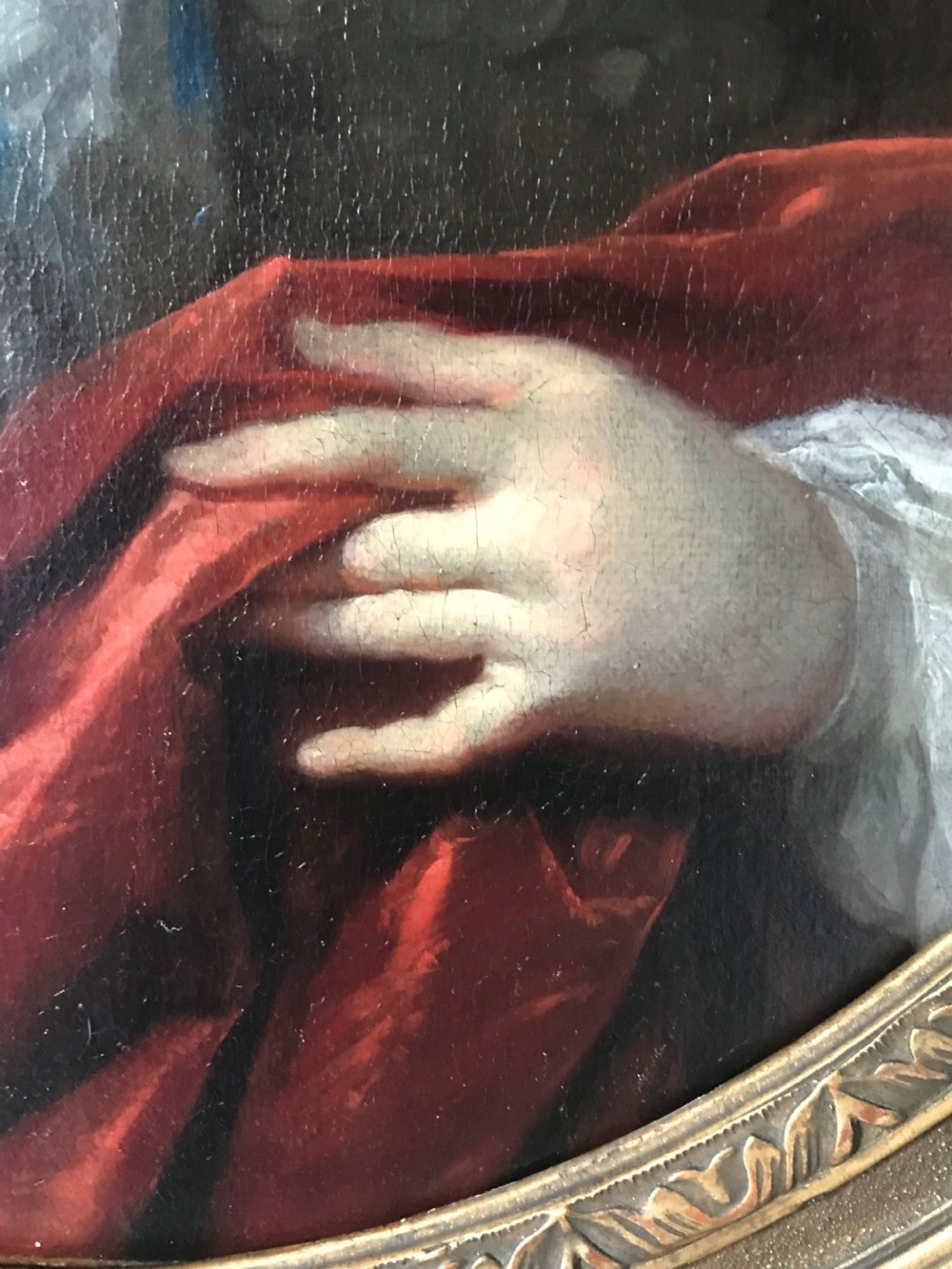 An oval seventeenth-century oil painting depicting a gentleman wearing a periwig and crimson cloak, set inside a carved giltwood frame. View IV