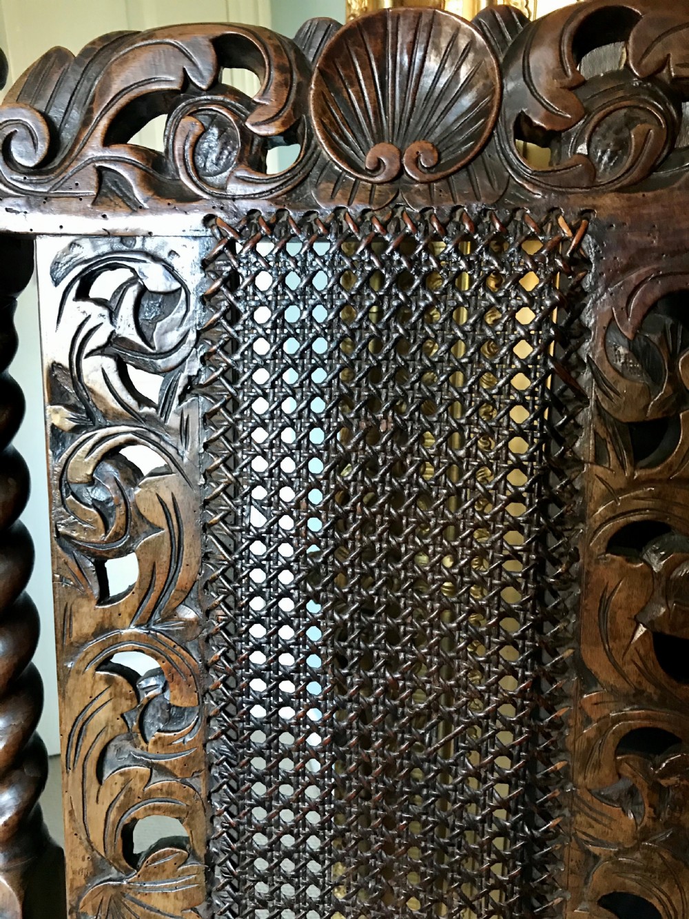 A 17th-century James II carved walnut armchair featuring spiral barley-twist uprights, detailed foliate carving, a central shell cresting, and woven cane back panel and seat. View IV