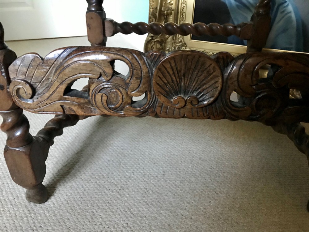 A 17th-century James II carved walnut armchair featuring spiral barley-twist uprights, detailed foliate carving, a central shell cresting, and woven cane back panel and seat. View VI