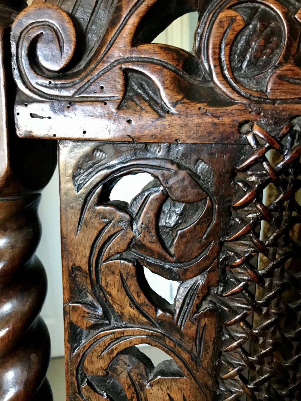 A 17th-century James II carved walnut armchair featuring spiral barley-twist uprights, detailed foliate carving, a central shell cresting, and woven cane back panel and seat. View VII