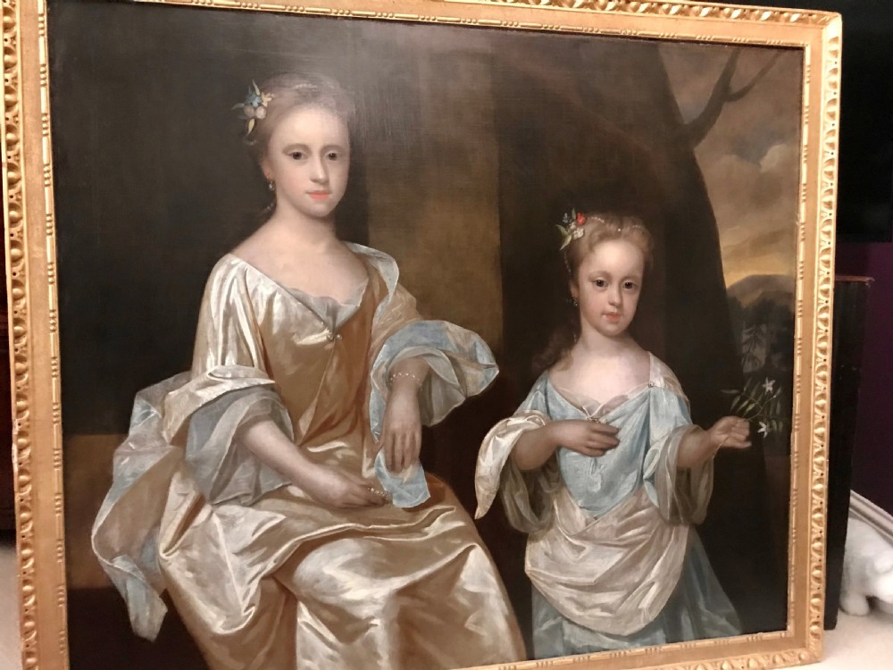 An early 18th-century oil painting depicting two young sisters in silk dresses set against a dark landscape within a gold leaf frame.