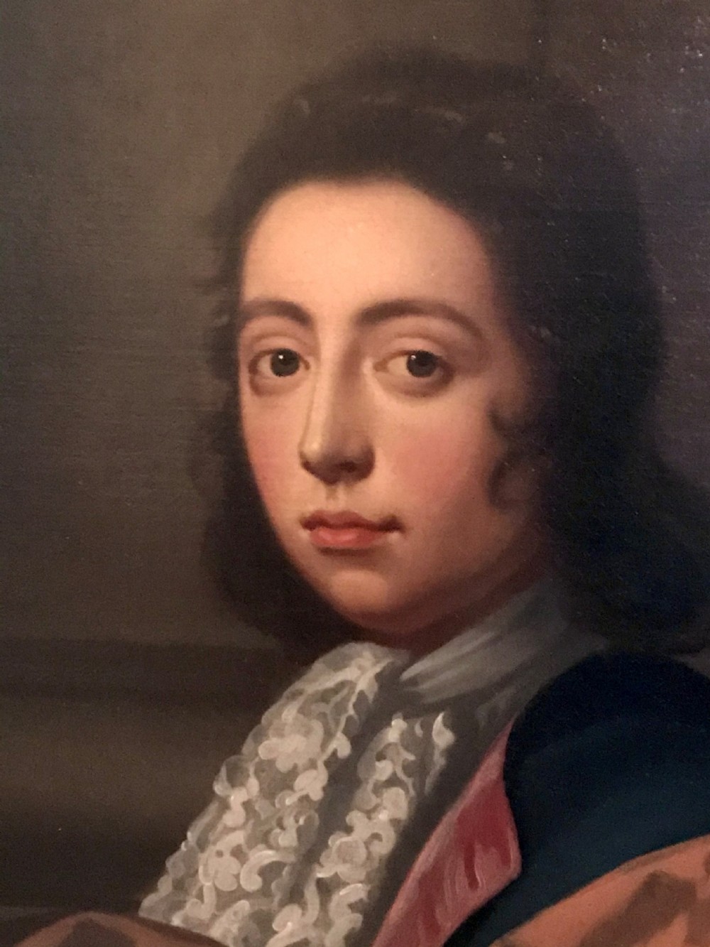 A seventeenth-century oil painting depicting a young gentleman in brown drapery and lace cravat set in a deeply carved giltwood frame. View II