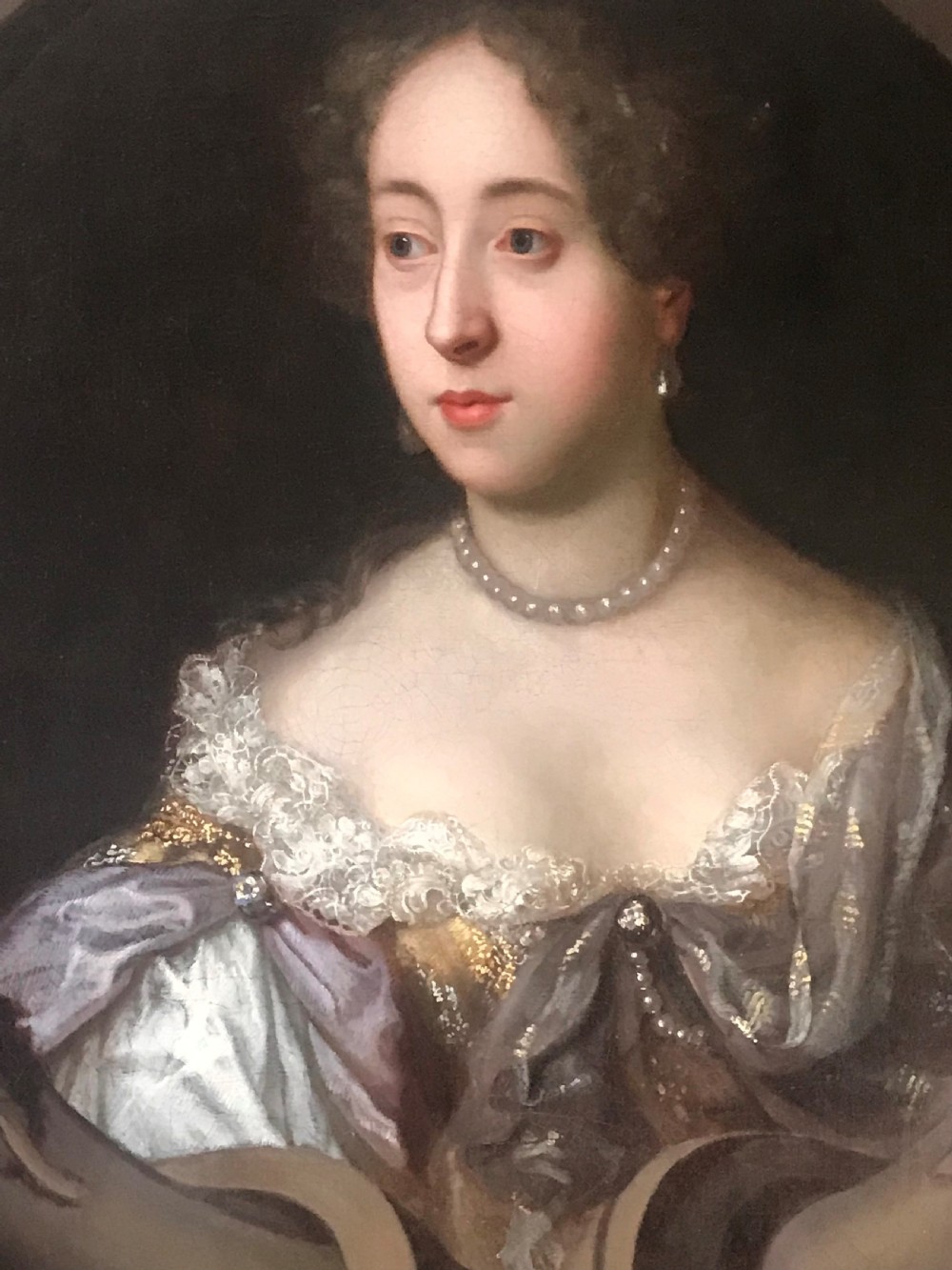 An oil portrait of a 17th-century lady with brown hair wearing a pearl necklace and draped gown, presented within a carved gold leaf frame. View II