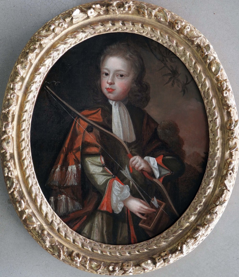 An oval Baroque oil painting depicting a young boy holding a bow, set within an ornate carved giltwood frame. View VI