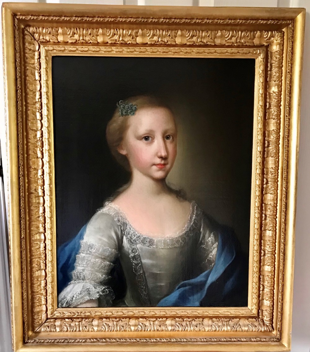 An 18th-century oil portrait depicting a young girl in a lace-trimmed dress and blue shawl, presented within a carved giltwood frame.