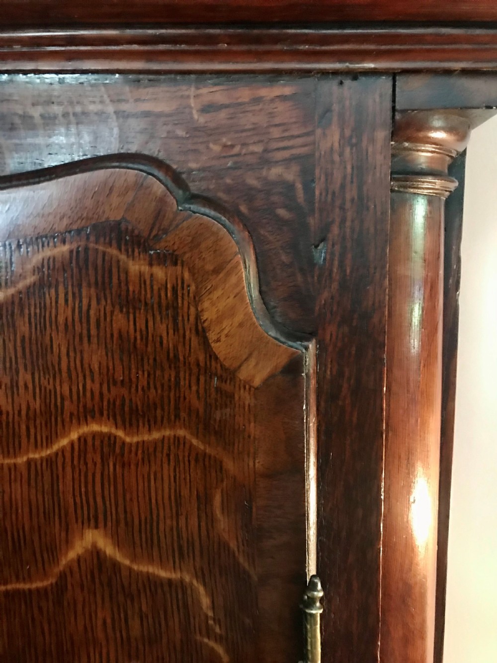 An 18th-century dark oak longcase clock featuring a square brass dial, moulded hood, and a shaped door on the main body. View VIII
