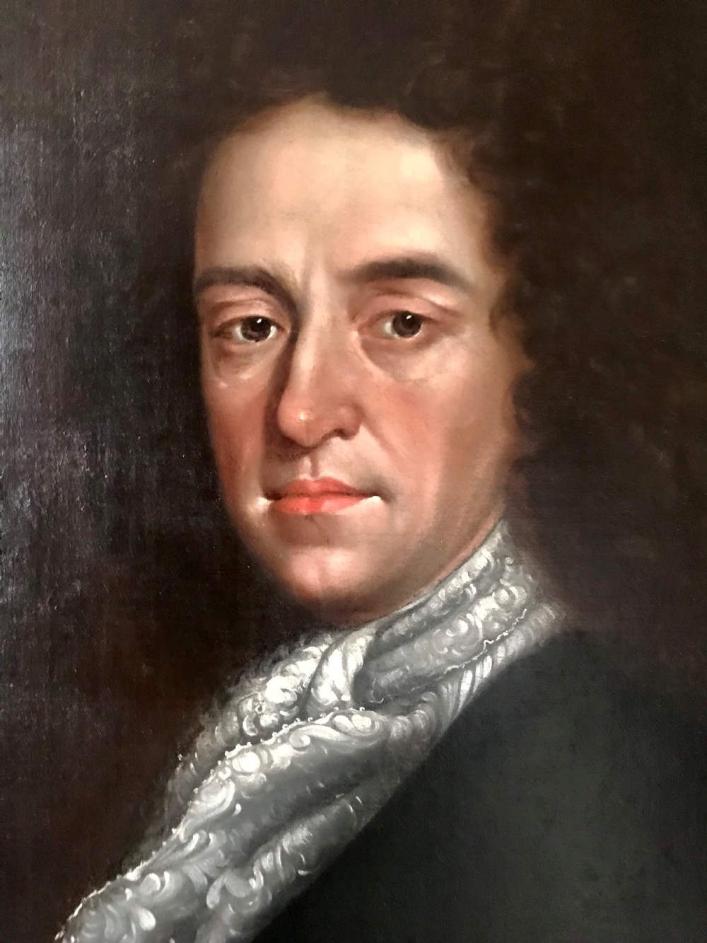 A late 17th-century Scottish oil portrait depicting a gentleman with a dark full-bottomed wig and lace cravat set within a painted feigned oval and carved gilded wooden frame. View III