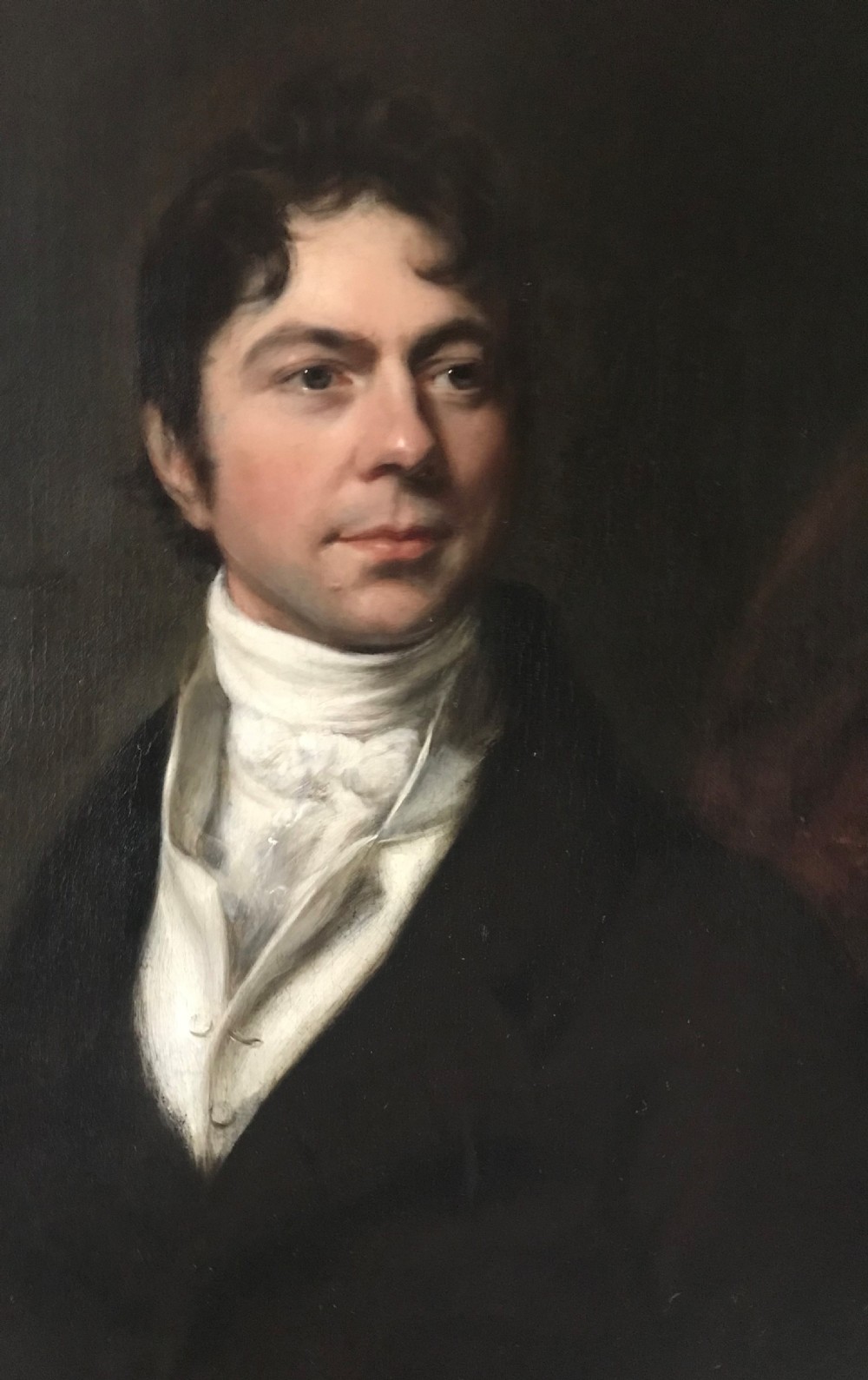 A Georgian oil portrait depicting a gentleman in a dark coat and white cravat, set within an ornate carved gilt frame. View II
