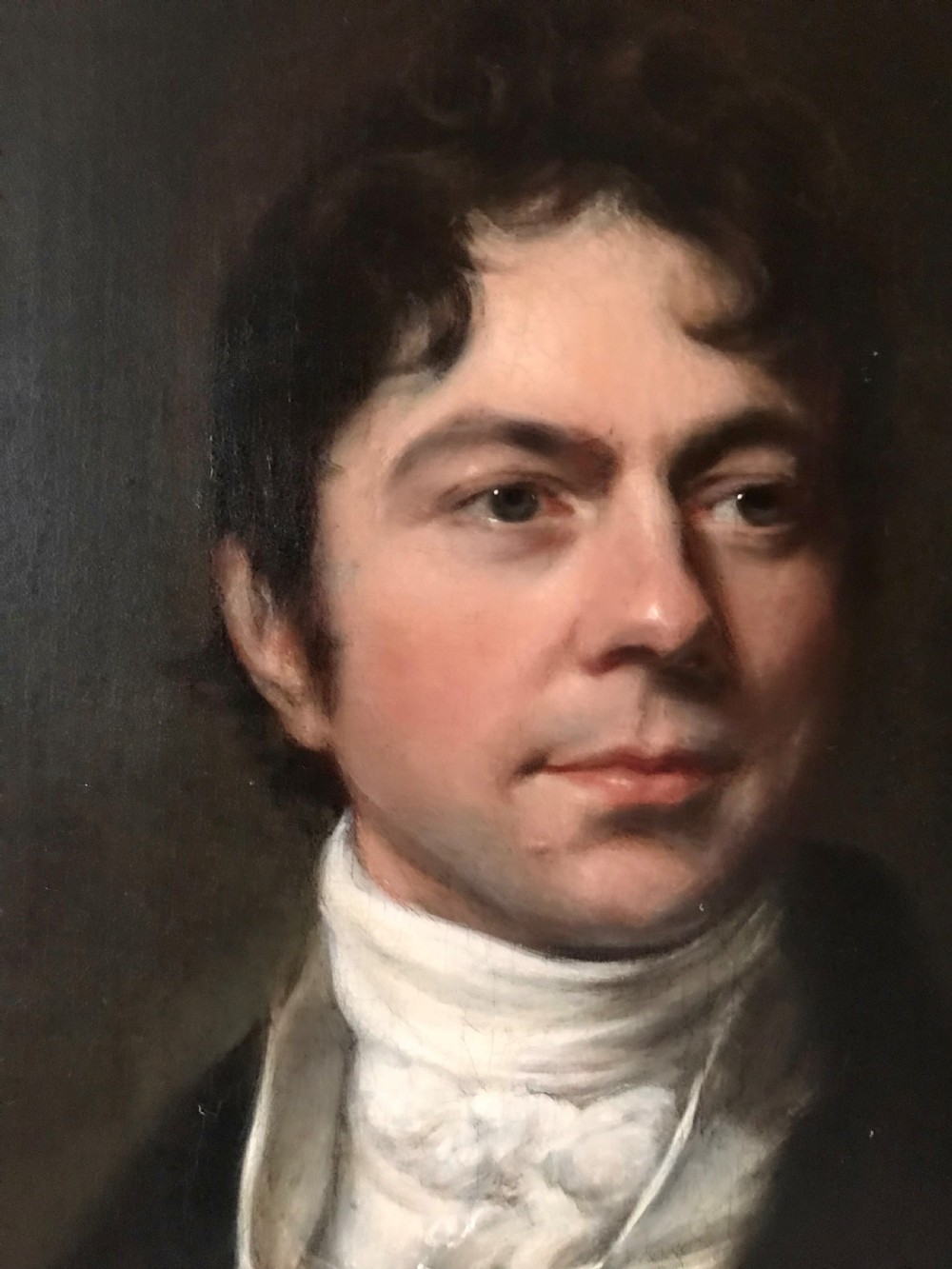 A Georgian oil portrait depicting a gentleman in a dark coat and white cravat, set within an ornate carved gilt frame. View III