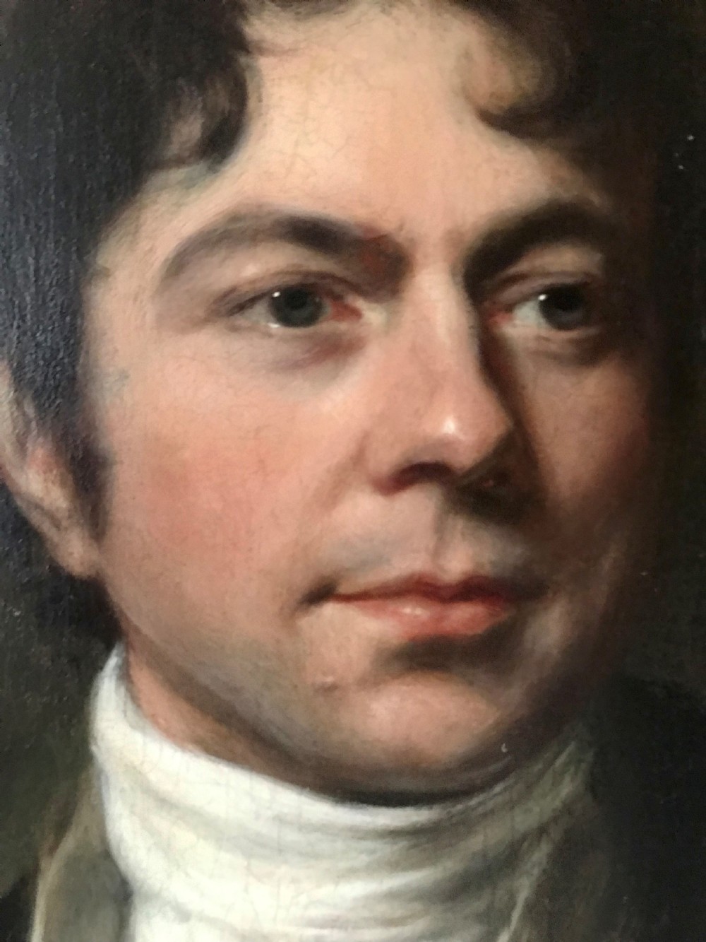 A Georgian oil portrait depicting a gentleman in a dark coat and white cravat, set within an ornate carved gilt frame. View IV