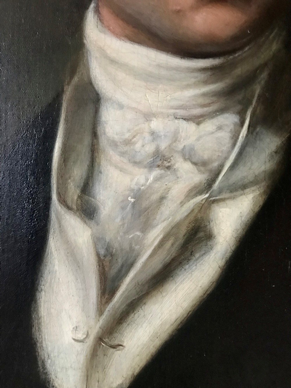 A Georgian oil portrait depicting a gentleman in a dark coat and white cravat, set within an ornate carved gilt frame. View V