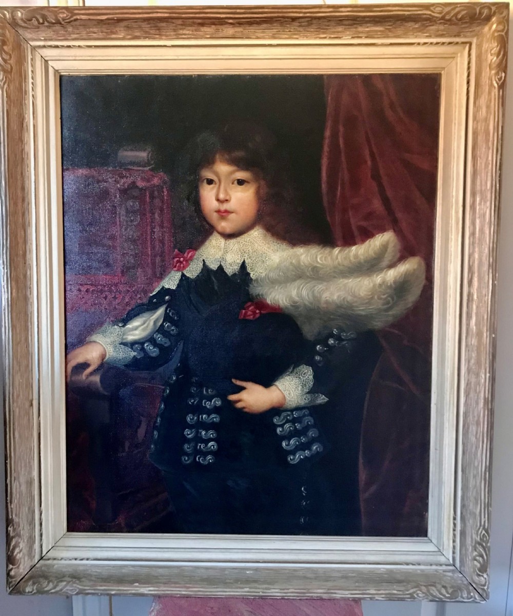 A framed oil painting depicting a child in dark 17th-century attire with a white lace collar holding a feathered hat.