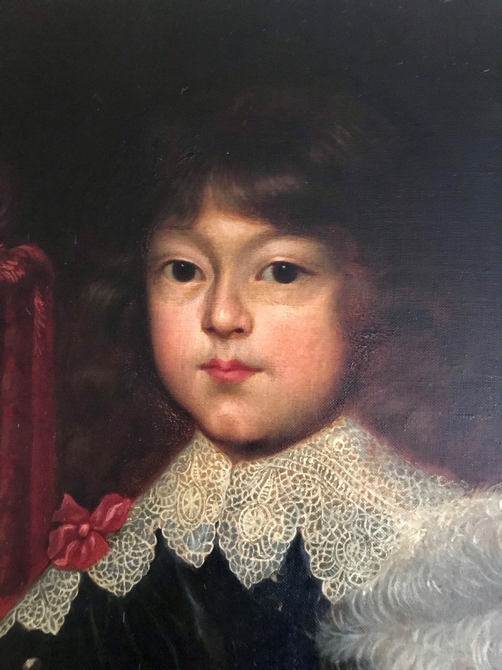 A framed oil painting depicting a child in dark 17th-century attire with a white lace collar holding a feathered hat. View III