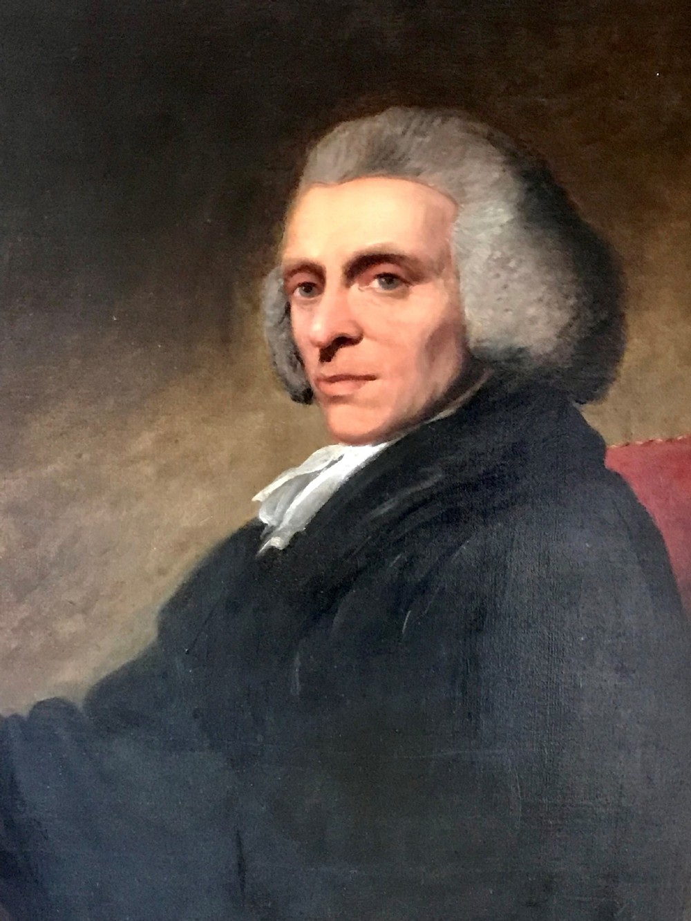 A late 18th-century oil portrait of a seated clergyman wearing a powdered wig and dark coat, set within a moulded gilded frame. View II