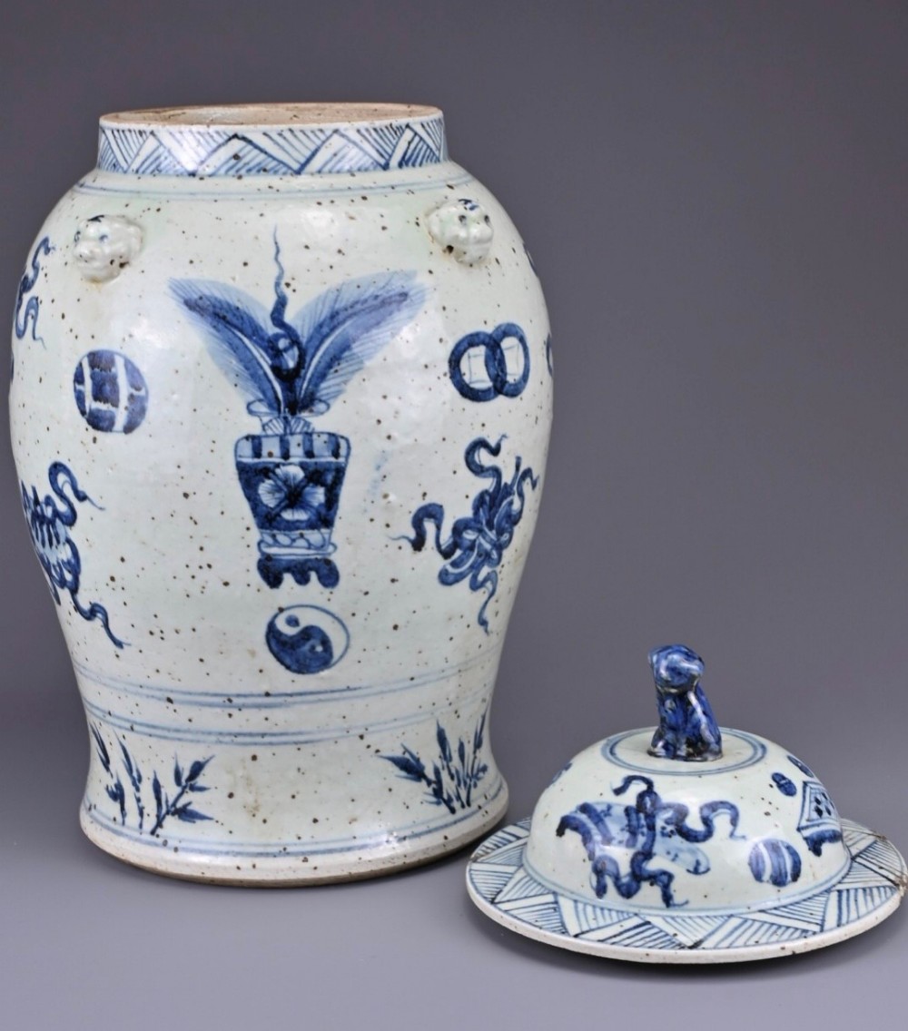A baluster-shaped Chinese porcelain jar decorated with underglaze cobalt blue auspicious symbols and a lid topped with a sculpted lion finial.