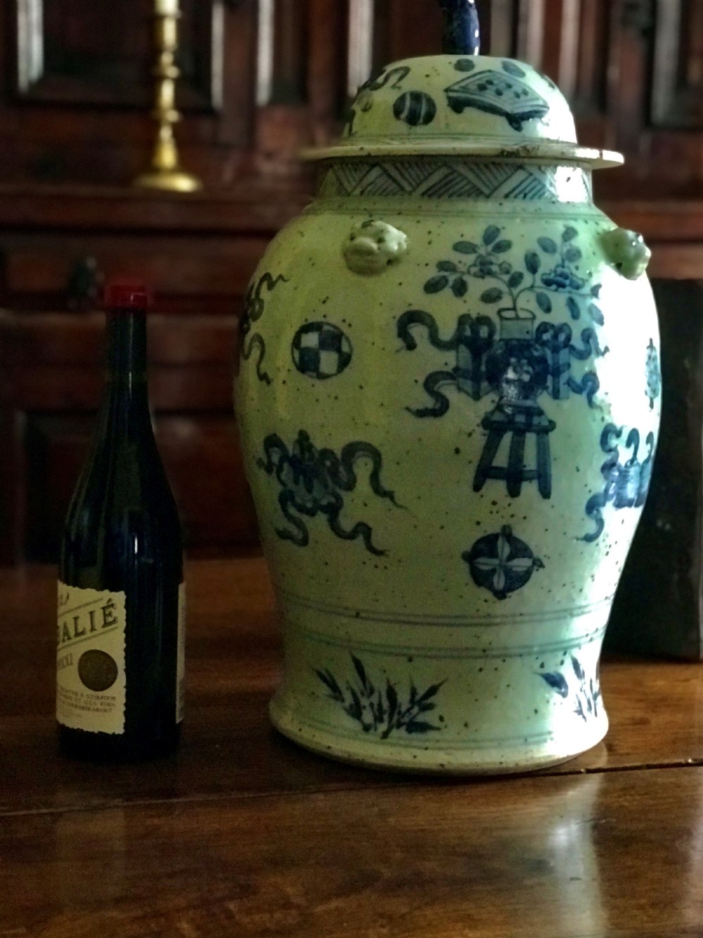 A baluster-shaped Chinese porcelain jar decorated with underglaze cobalt blue auspicious symbols and a lid topped with a sculpted lion finial. View V