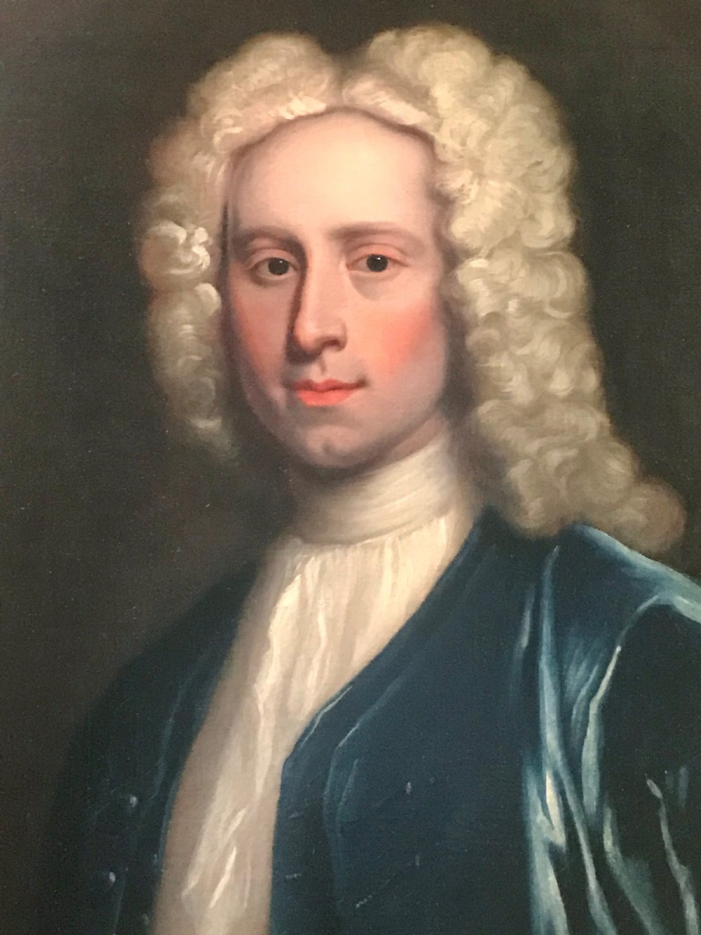 An 18th-century oil portrait depicting a gentleman wearing a powdered wig and blue coat within a carved giltwood frame. View II
