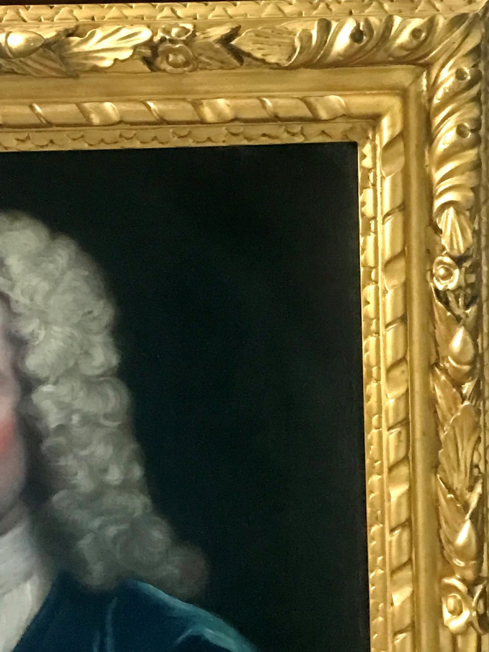 An 18th-century oil portrait depicting a gentleman wearing a powdered wig and blue coat within a carved giltwood frame. View III