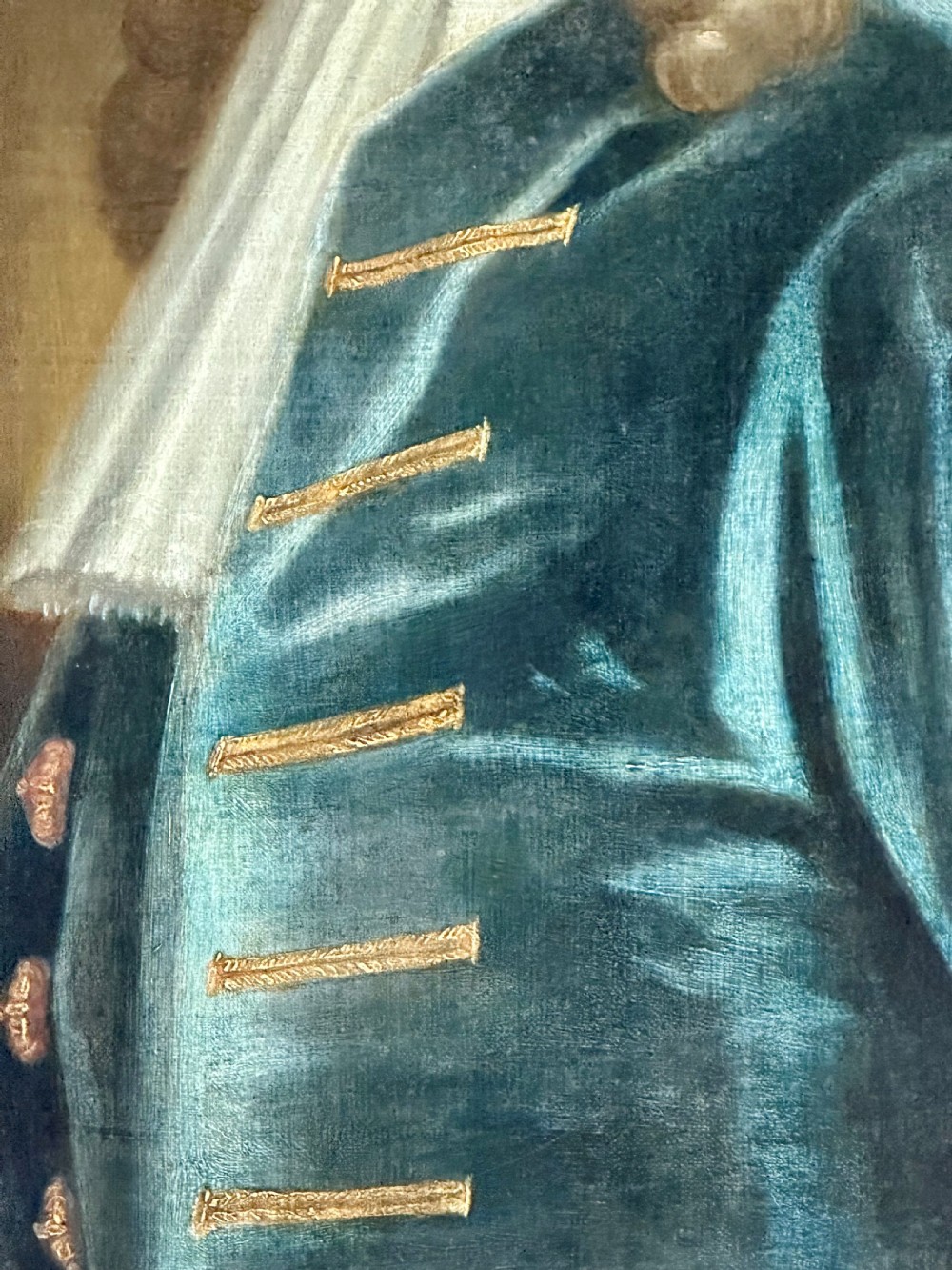 An 18th-century oil portrait painting depicting a gentleman with a long wig, white cravat, and teal blue coat, set within a carved gold frame. View IV