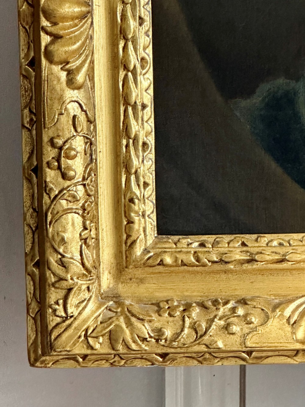 An 18th-century oil portrait painting depicting a gentleman with a long wig, white cravat, and teal blue coat, set within a carved gold frame. View V