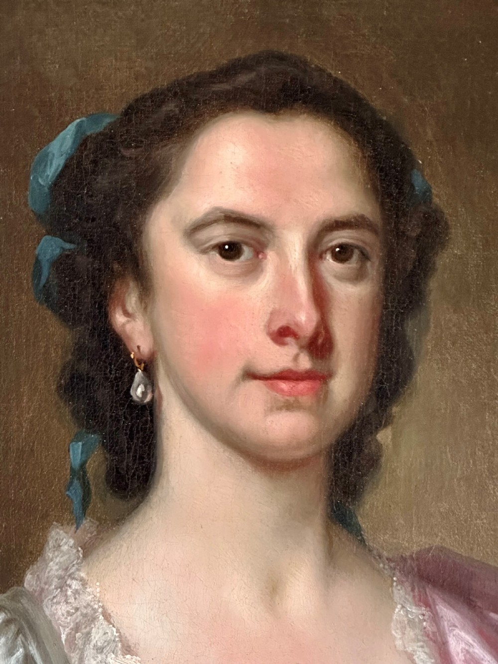 An 18th-century oil portrait of a woman in a pink and white dress set within a feigned oval and enclosed by a gold carved giltwood frame. View III