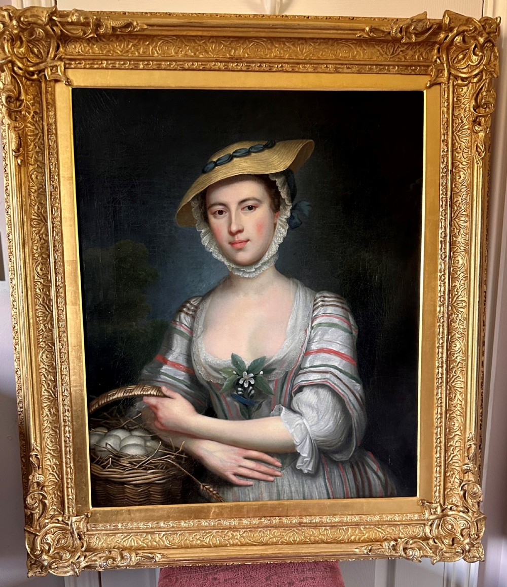 An eighteenth-century oil portrait on canvas depicting a woman in a striped dress and straw hat holding a basket of eggs, presented in an ornate giltwood frame.