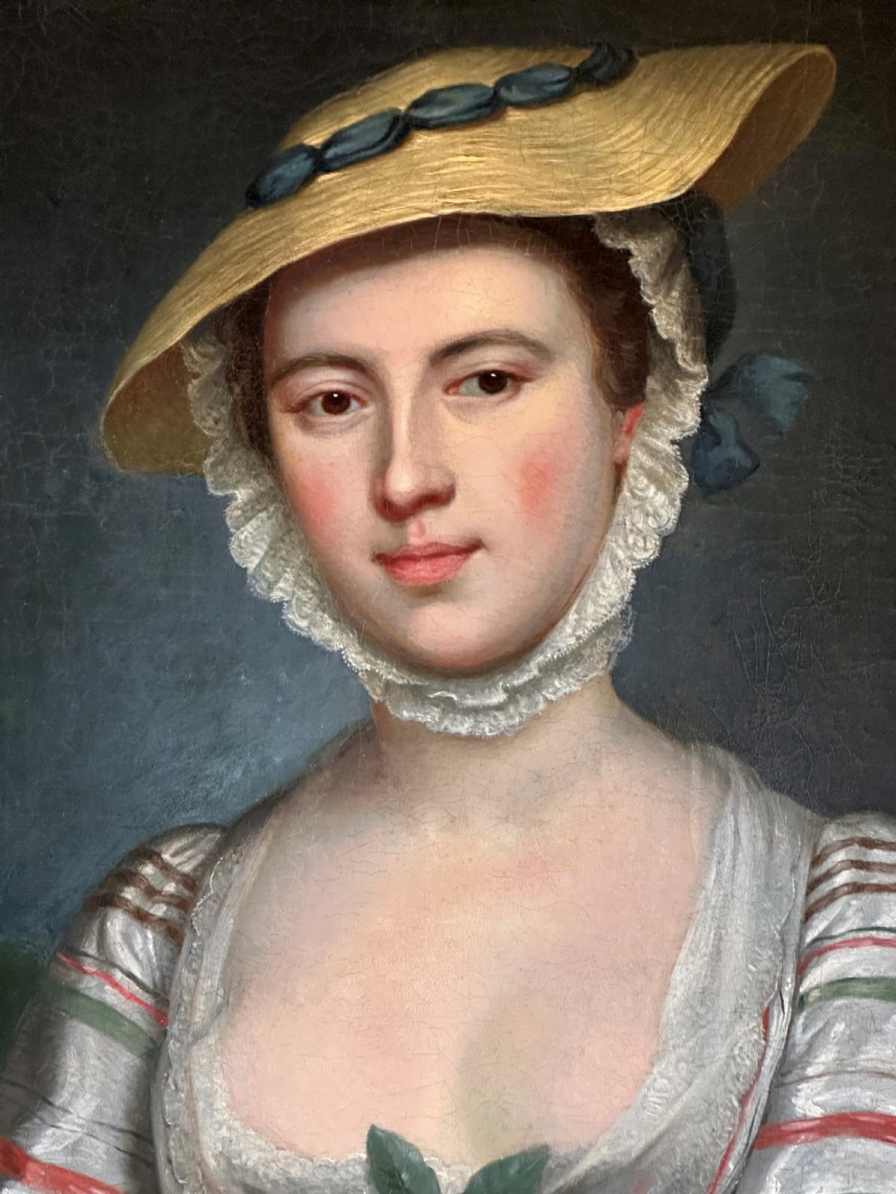 An eighteenth-century oil portrait on canvas depicting a woman in a striped dress and straw hat holding a basket of eggs, presented in an ornate giltwood frame. View III