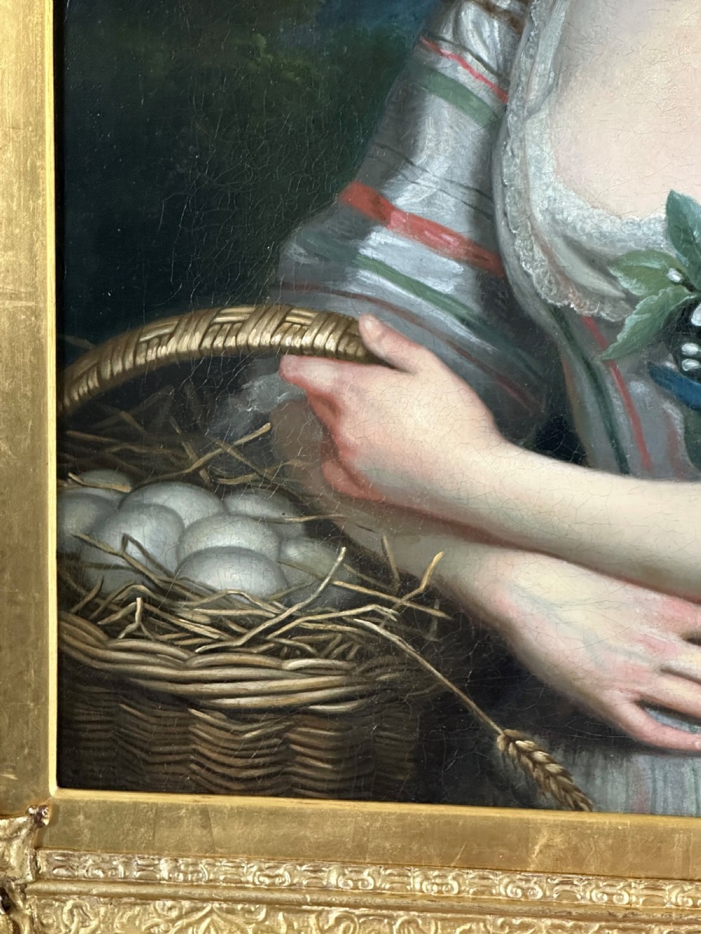 An eighteenth-century oil portrait on canvas depicting a woman in a striped dress and straw hat holding a basket of eggs, presented in an ornate giltwood frame. View IV