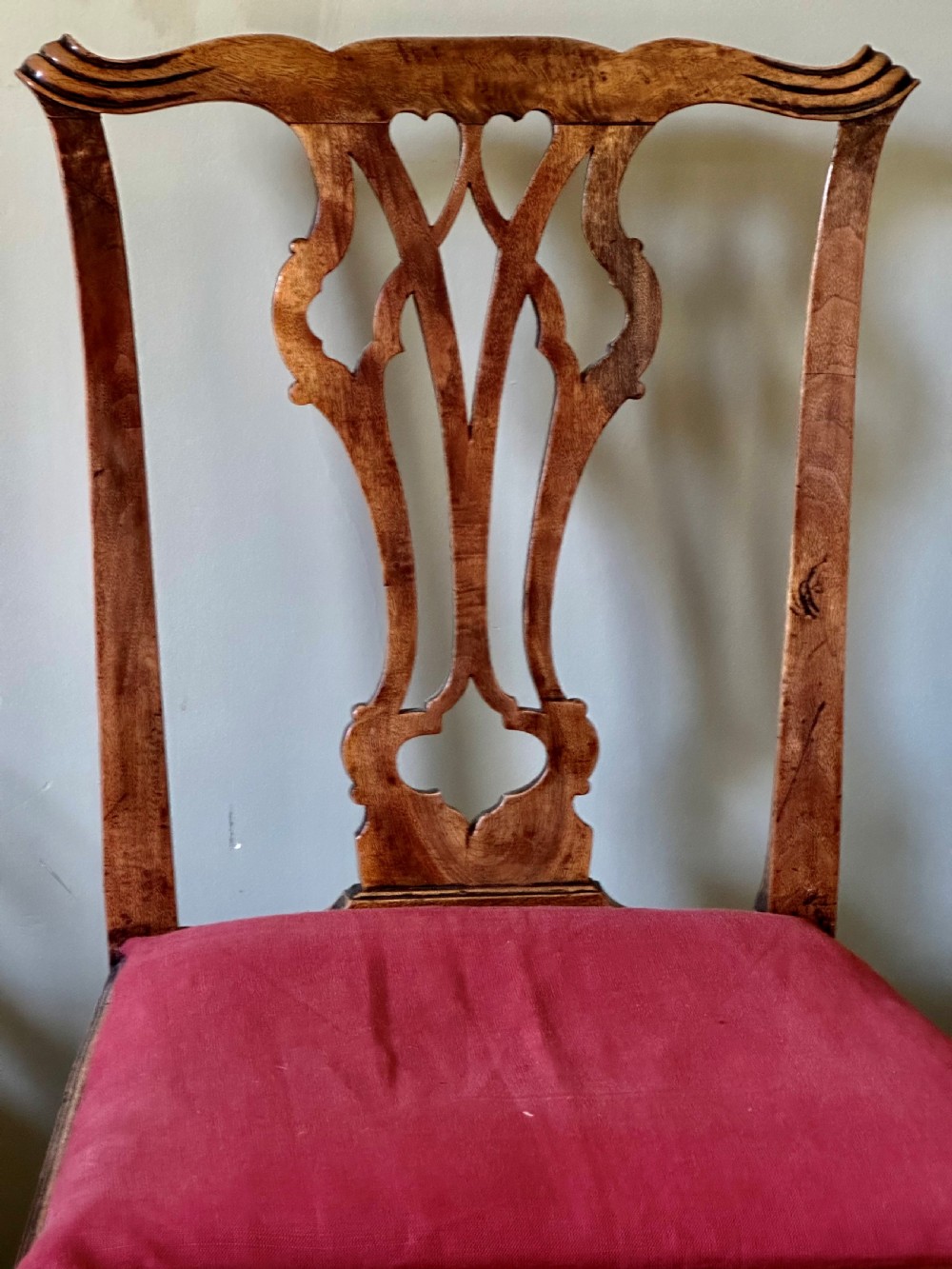 An 18th-century country Chippendale side chair featuring a carved pierced back splat, a square seat upholstered in red fabric, and straight legs joined by stretchers. View II