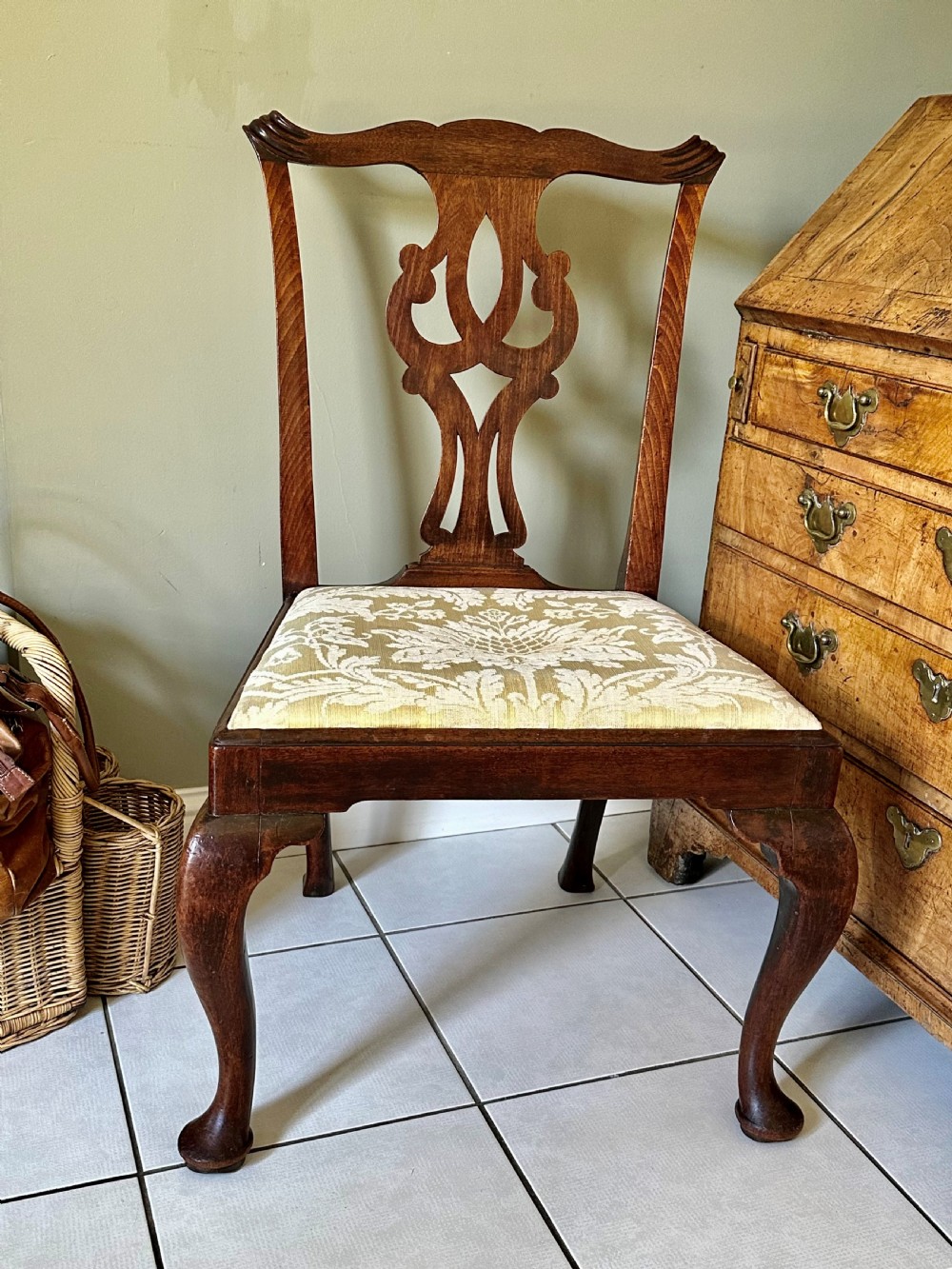 A George II walnut side chair featuring a carved pierced back splat, an upholstered drop-in seat, and front cabriole legs with pad feet.