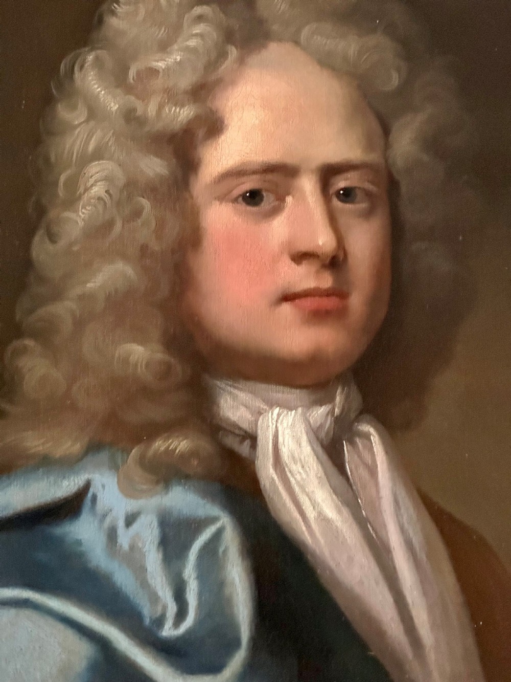 An 18th-century oil painting depicting a gentleman with a grey wig, white cravat, and blue mantle, housed within a carved gilded frame. View II