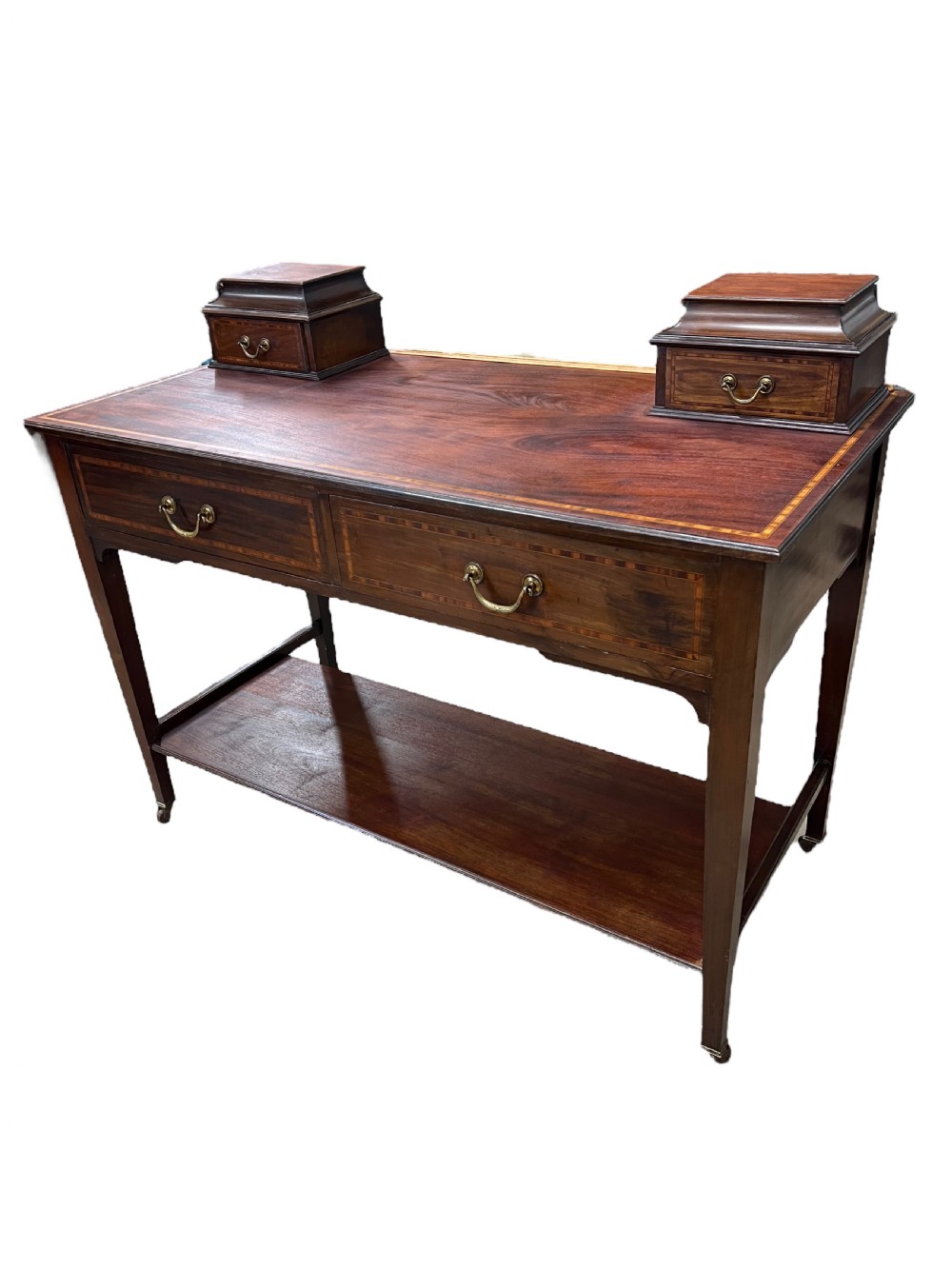 An Edwardian mahogany dressing table featuring satinwood crossbanding, two frieze drawers, two raised corner drawers, a lower shelf, and brass castors.