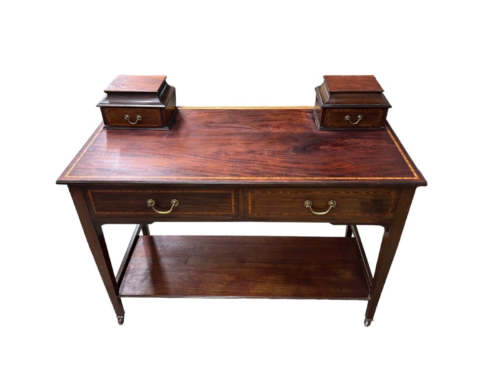 An Edwardian mahogany dressing table featuring satinwood crossbanding, two frieze drawers, two raised corner drawers, a lower shelf, and brass castors. View IV