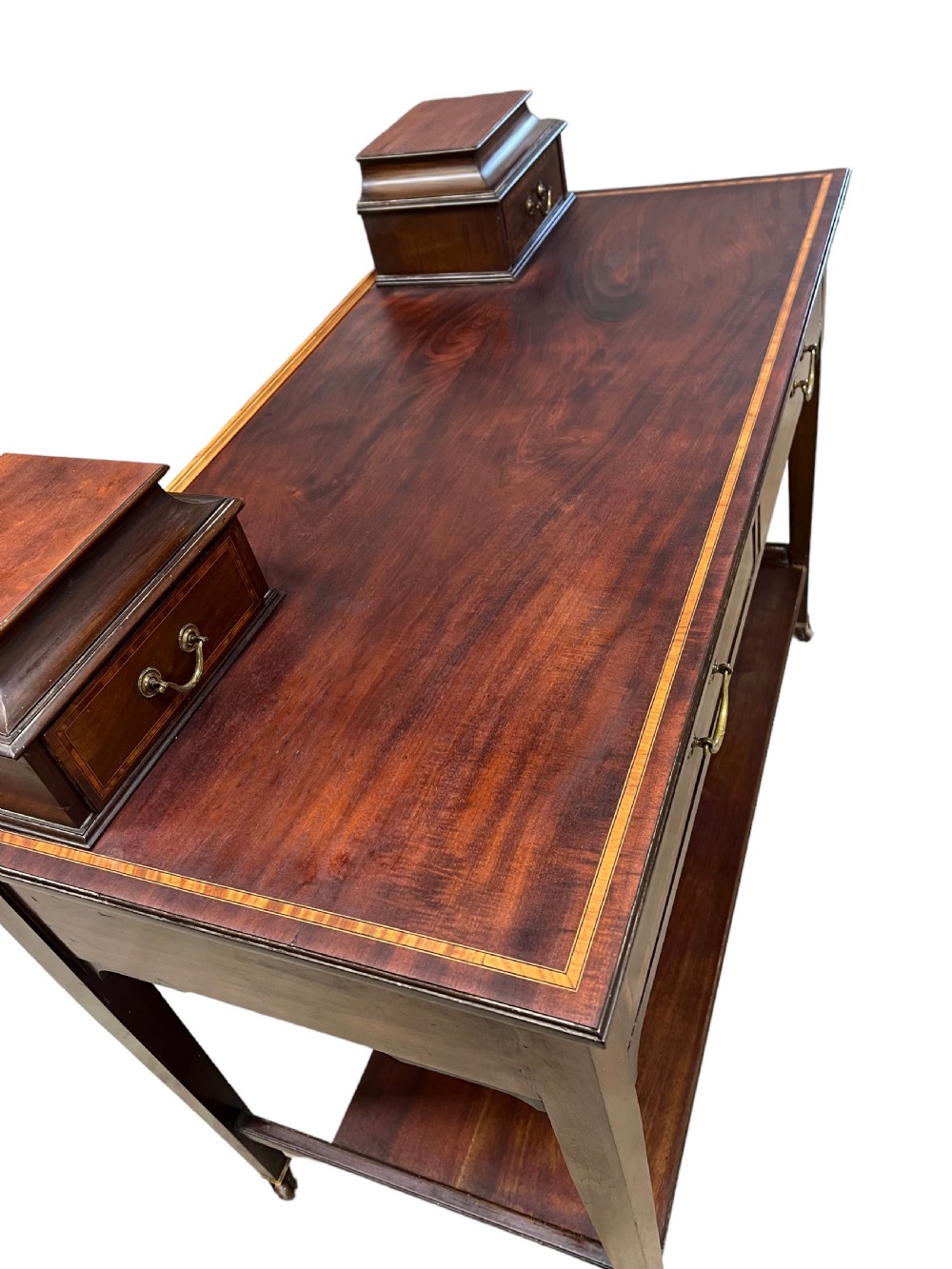 An Edwardian mahogany dressing table featuring satinwood crossbanding, two frieze drawers, two raised corner drawers, a lower shelf, and brass castors. View VI