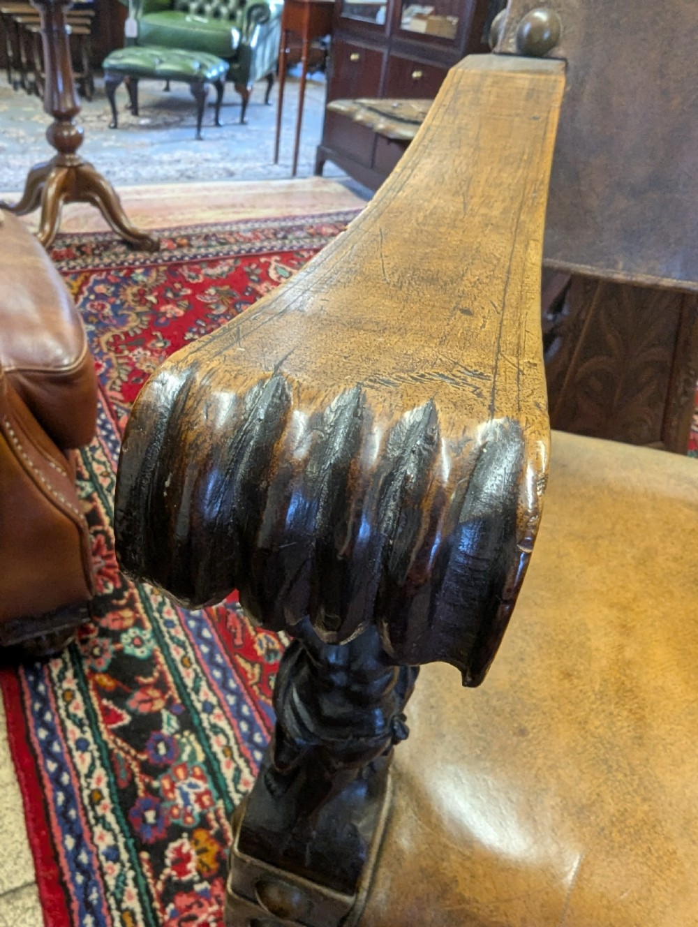 An 18th-century European walnut throne chair featuring high-backed studded leather upholstery, carved armrests, finials, and an ornate lower stretcher. View III