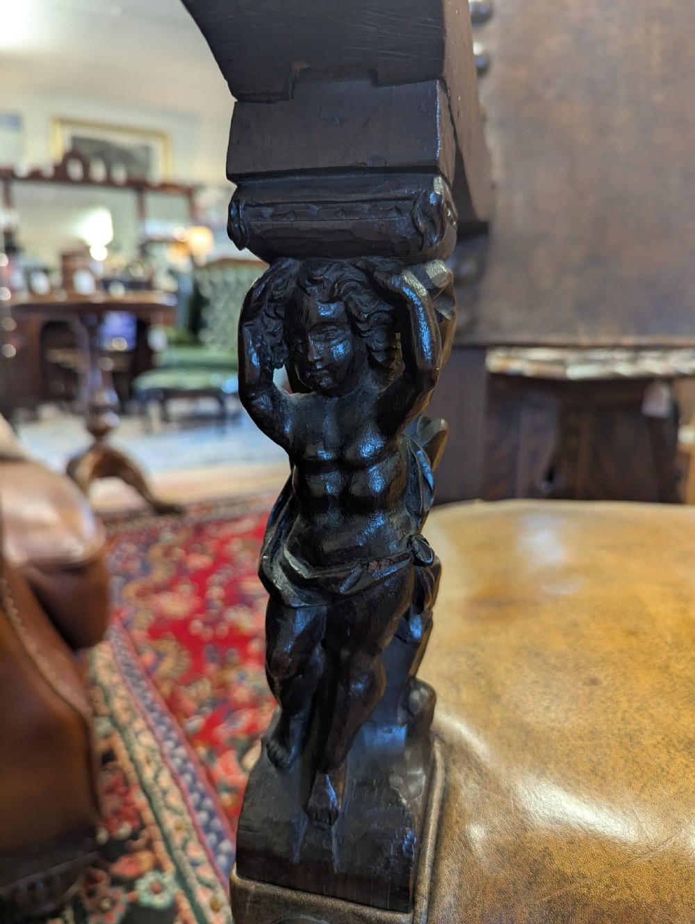 An 18th-century European walnut throne chair featuring high-backed studded leather upholstery, carved armrests, finials, and an ornate lower stretcher. View IV