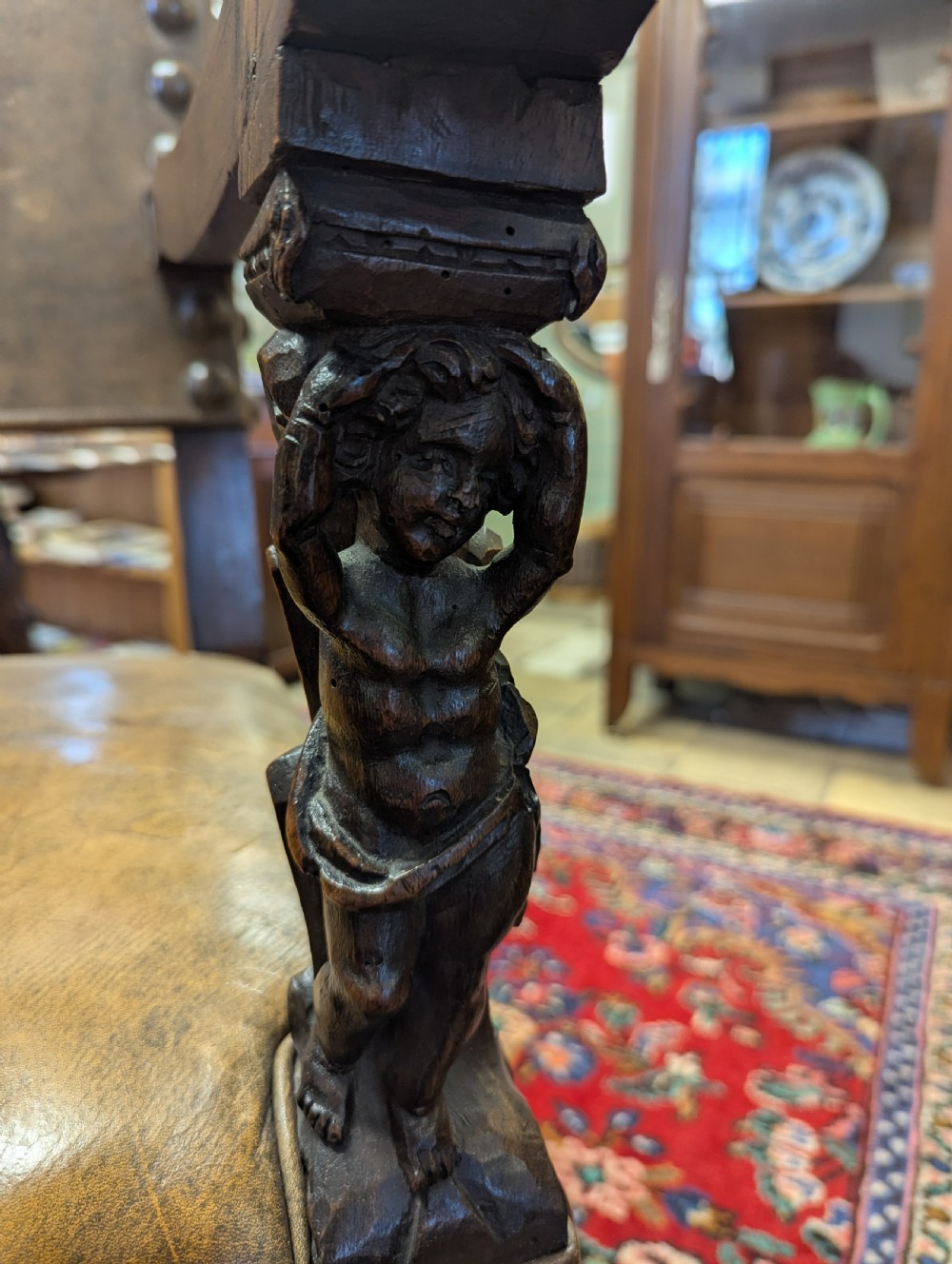 An 18th-century European walnut throne chair featuring high-backed studded leather upholstery, carved armrests, finials, and an ornate lower stretcher. View V
