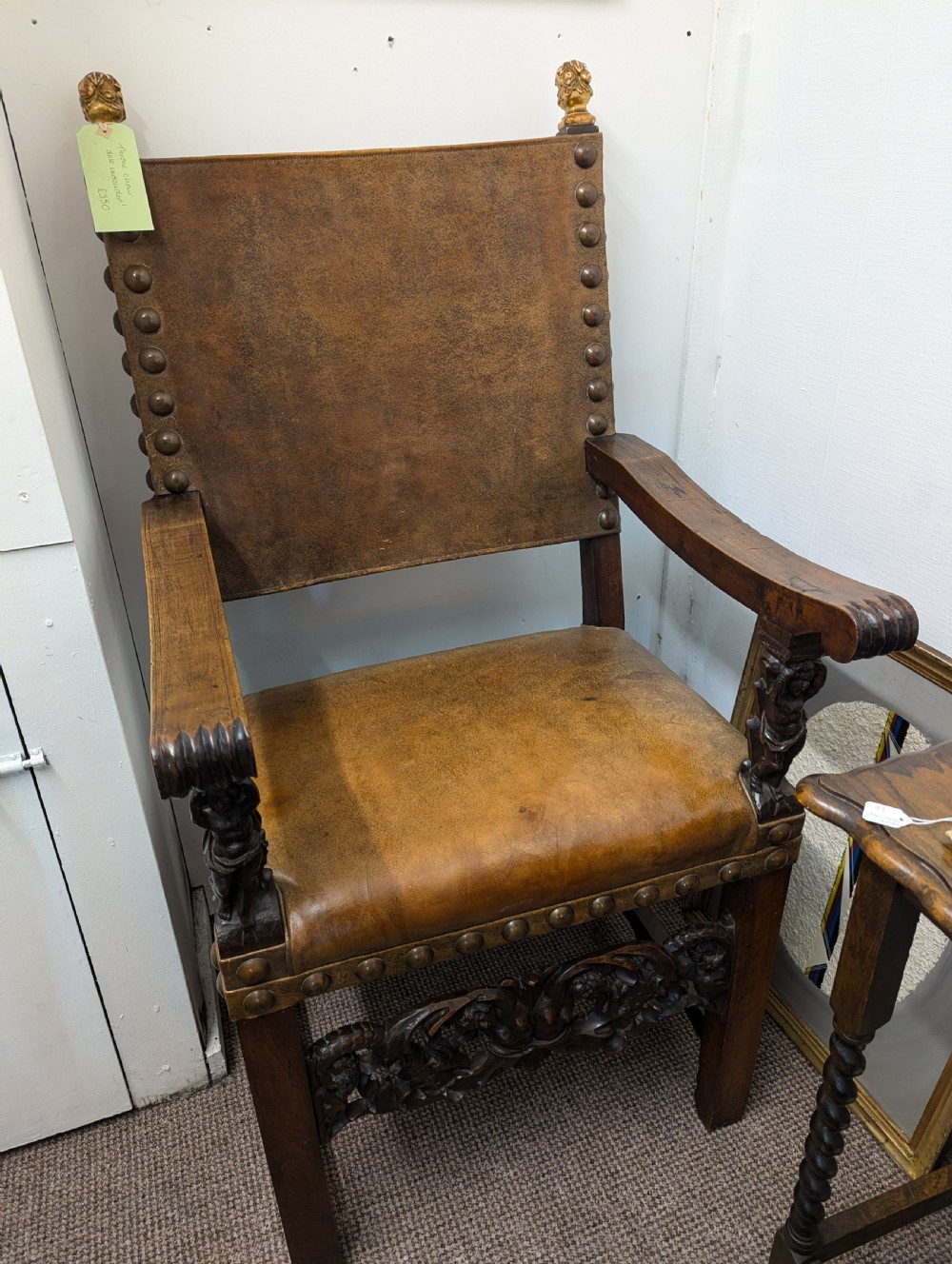 An 18th-century European walnut throne chair featuring high-backed studded leather upholstery, carved armrests, finials, and an ornate lower stretcher. View VIII