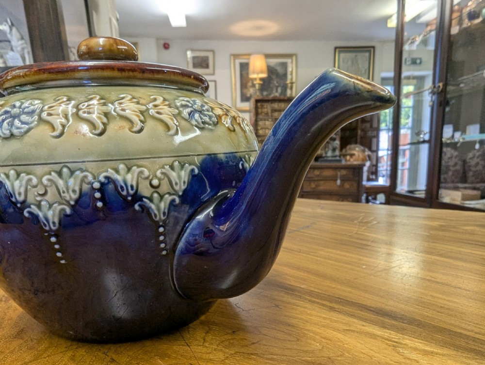 An Art Nouveau Royal Doulton stoneware teapot featuring a cobalt blue base, an olive green shoulder with raised relief patterns, and a fitted lid. View III