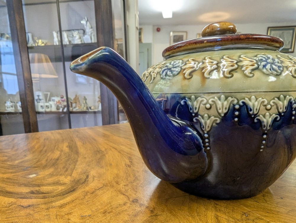 An Art Nouveau Royal Doulton stoneware teapot featuring a cobalt blue base, an olive green shoulder with raised relief patterns, and a fitted lid. View IV