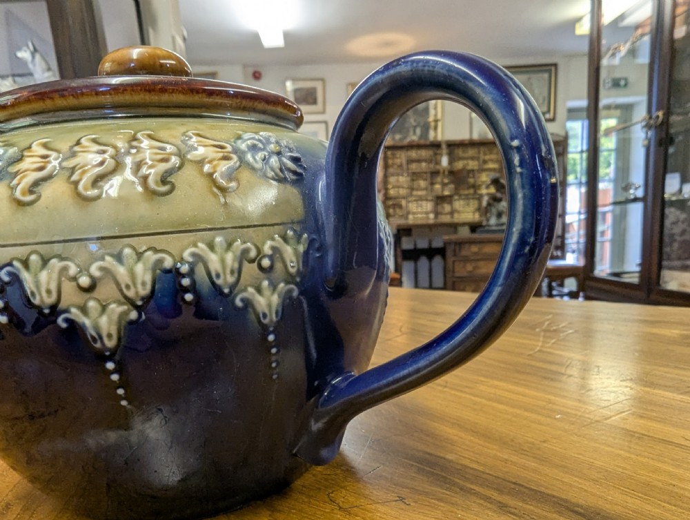 An Art Nouveau Royal Doulton stoneware teapot featuring a cobalt blue base, an olive green shoulder with raised relief patterns, and a fitted lid. View V