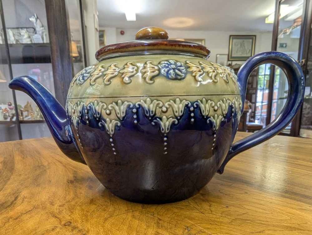 An Art Nouveau Royal Doulton stoneware teapot featuring a cobalt blue base, an olive green shoulder with raised relief patterns, and a fitted lid. View VI